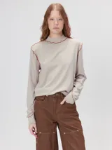 Polera de cuello alto confeccionada en tela rib color blanco, con mangas largas y hombreras. Presenta pespuntes en contraste en las terminaciones del cuello, hombros y puños.