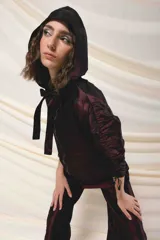 Capucha deportiva color borgoña, confeccionada en tafeta tornasolada. Se ajusta con dos tiras que pueden anudarse formando un lazo.