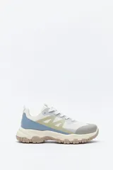 Zapatilla deportiva de inspiración outdoor con diseño de paneles en tonos neutros, que combina malla y materiales sintéticos. Presenta una suela robusta con relieve dentado para mayor tracción y estabilidad.