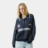 Polo de punto de manga larga con diseño de rayas verticales blancas sobre fondo azul marino. Presenta cuello tipo polo con solapa, corte holgado y detalles bordados y tipo parche en el frente con el logo de la marca.