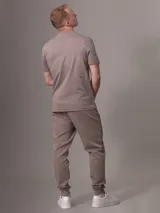 Pantalón de jogging color topo, con cintura elástica ajustable con cordón, puños ajustados y bolsillos laterales con cierre.