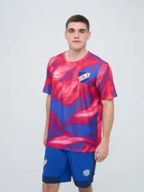 Remera de entrenamiento Umbro del Club Nacional de Football, modelo Press, para hombre. Diseño en tonos de rojo con patrón estampado tipo humo o abstracto, cuello redondo y mangas cortas. Incluye el logo de Umbro y el escudo del club en el pecho.