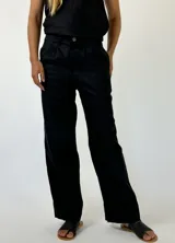 Pantalón negro de lino, corte recto, con pinzas en la cintura y ruedo desflecado.