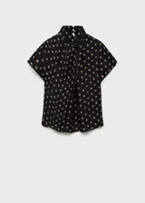 Blusa de viscosa con cuello alto drapeado y mangas cortas. Presenta un diseño recto con estampado de topos en tonos contrastantes sobre fondo negro.