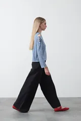 Remera de manga larga a rayas horizontales blancas y negras, con escote redondo y aberturas en los hombros sujetas con lazos regulables de tela a rayas.