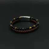 Pulsera doble para hombre que combina una tira de cuero trenzado marrón con una hilera de cuentas de piedra natural en tonos negros y marrones, unidas por un cierre magnético de acero inoxidable.