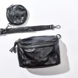 Bandolera negra de cuero sintético con correa ajustable y monedero redondo extraíble.