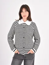 Buzo de punto a rayas horizontales blancas y negras, con cuello camisero blanco con volados y cierre frontal de botones.