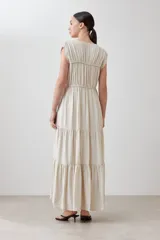 Maxi vestido color beige melange, con escote en V, mangas cortas y falda larga con volantes.