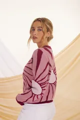 Sweater de punto color crema con diseño de flor en el frente, con detalles en lila y amarillo.