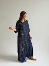 Vestido largo azul oscuro con diseño asimétrico que combina un lado liso con un lado estampado de hojas, manga corta y bolsillo frontal aplicado.