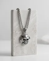 Collar de acero italiano con cadena de eslabones y dije en forma de calavera sobre una cruz.
