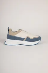 Zapatillas urbanas de gamuza color blanco, beige y celeste, con suela alta blanca y cordones blancos.