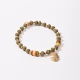 Pulsera elástica con cuentas facetadas color verde oliva, cuentas doradas y cuentas cilíndricas de colores. Incluye un dije dorado con textura irregular.