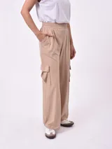 Pantalón cargo ancho de color beige claro, con cintura elástica fruncida y bolsillos tipo parche a los lados de las piernas.