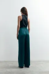 Pantalón largo de vestir color verde esmeralda, de tela satinada y corte palazzo.