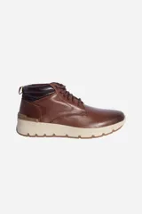 Bota de cuero marrón con cordones, caña media y suela de goma color beige.