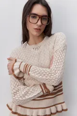 Sweater calado de algodón color celeste, con cuello redondo, mangas largas y diseño cómodo. Presenta puños, cintura y terminaciones acanaladas con rayas en contraste de color marrón.