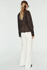 Chaqueta de gamuza marrón con cuello alto, manga larga y bajo con peplum. Cuenta con doble botonadura decorativa de botones metálicos dorados en el frente y cierre con ganchos ocultos.
