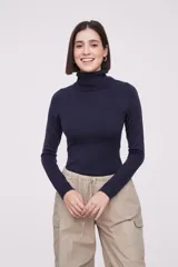 Polera de tejido de punto fino en color azul marino, con cuello alto y mangas largas. Presenta un ajuste al cuerpo y terminaciones acanaladas en cuello, puños y ruedo.
