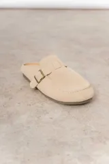 Zueco de cuero gamuzado color marrón, con diseño minimalista y elegante. Cuenta con una tira lateral con hebilla metálica regulable y plantilla acolchada. Su base es liviana y flexible.