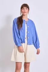 Cazadora azul de manga larga con puños elásticos, cuello redondo sin solapas y cierre frontal con botones grandes de color claro.