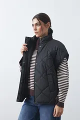 Chaleco acolchado de nylon con diseño capitoneado, cuello alto y cierre frontal con botones a presión. Presenta un calce amplio y versátil.