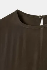 Blusa de cuello redondo y manga larga, confeccionada en tejido fluido con acabado satinado. Presenta un diseño de corte holgado, bajo recto y cierre en la espalda mediante una pequeña abertura con botón.