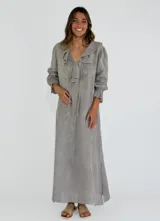 Vestido largo color beige de lino, con escote en V, volados en el escote y mangas largas con puños elásticos.