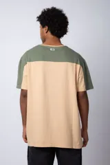Remera de algodón con diseño color block, combinando tonos beige y verde militar. Presenta cuello redondo y estampa frontal con la frase 'Pan y Vino' y el logo 'VCP Argentina'.