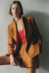 Blazer entallado color tostado confeccionado con lino. Cuenta con cuello solapa, manga larga con hombreras y cierre frontal con dos botones forrados a tono. Presenta forrería interior blanca.