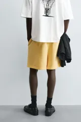 Bermuda de algodón gris con efecto lavado, corte relajado, cintura elástica ajustable con cordón y bolsillos laterales y trasero de vivo.