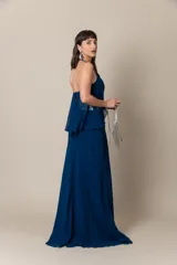 Vestido largo de fiesta color azul, confeccionado en gasa con corsé drapeado y breteles bordados. Presenta una capa de gasa que nace de los breteles. Incluye un cinturón plateado.