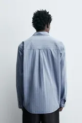 Camisa de corte regular fit confeccionada en tejido compacto de algodón. Presenta un diseño de rayas verticales, cuello abotonado, manga larga con puños abotonados y cierre frontal con botones.