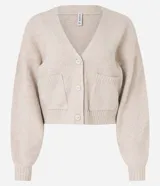 Cardigan corto de punto color beige claro, con escote en V, manga larga abullonada y cierre frontal de botones. Posee bolsillos delanteros tipo parche.