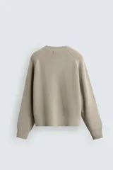 Jersey de punto con diseño boxy fit, cuello redondo y manga larga. Presenta una textura acanalada y acabados en rib en puños y ruedo.