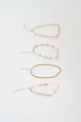 Set de cuatro brazaletes dorados con diferentes diseños: uno de eslabones tipo concha, uno con perlas engarzadas, uno de cadena fina y uno con eslabones en forma de espiga.
