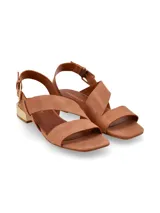 Sandalias de cuero color marrón tostado, con tiras asimétricas cruzadas, taco bajo rectangular con detalle metálico dorado y tira ajustable con hebilla en el talón.