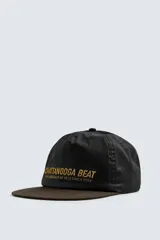Gorra de algodón negra con visera plana de color marrón oscuro. Presenta bordado frontal en hilo dorado con el texto "CHATTANOOGA BEAT THE LANGUAGE OF JAZZ SINCE 1920".