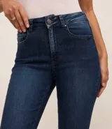 Pantalón de jean acampanado de tiro alto, color azul oscuro, con bolsillos delanteros y traseros, y cierre con botón y cremallera.