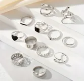 Set de 27 anillos plateados con diferentes diseños: lisos, con forma de serpiente, con corazones, con piedras negras, con forma de mariposa y con eslabones.