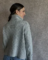 Sweater de lana color crudo con cuello alto y diseño trenzado.