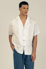 Camisa estilo camper, de fit boxy, confeccionada en popelina con estampa de mármol celeste y blanco. Tiene cuello tipo camp-collar y botones de madera.
