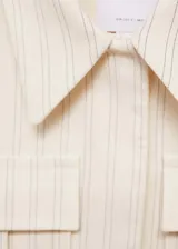 Chaqueta corta de diseño recto con cuello camisero y cierre frontal de botones ocultos. Presenta un estampado de rayas verticales finas, dos bolsillos de parche en la parte delantera y manga larga.