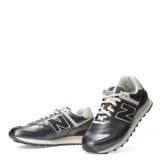 Championes urbanos New Balance modelo 574, color gris metalizado con detalles en crema y blanco. Presentan el logo N característico en los laterales, cordones al tono y suela con tecnología de amortiguación.