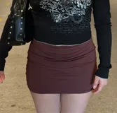Minifalda marrón ajustada con diseño fruncido en la parte superior y corte recto.
