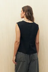 Top sin mangas de lino y viscosa, color negro, con escote redondo y caída relajada. Presenta hombros levemente marcados y botones forrados en la espalda.