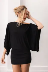 Blusa fluida de color marrón, con diseño holgado, escote bote que deja un hombro al descubierto y mangas anchas y cortas.