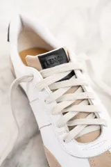 Zapatillas bajas de cuero blanco con puntera y talón en gamuza color beige. Ajuste con cordones y suela marrón.