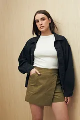 Short pollera color marrón de tiro alto, confeccionado en algodón. Presenta solapa frontal que simula una falda y bolsillos delanteros.